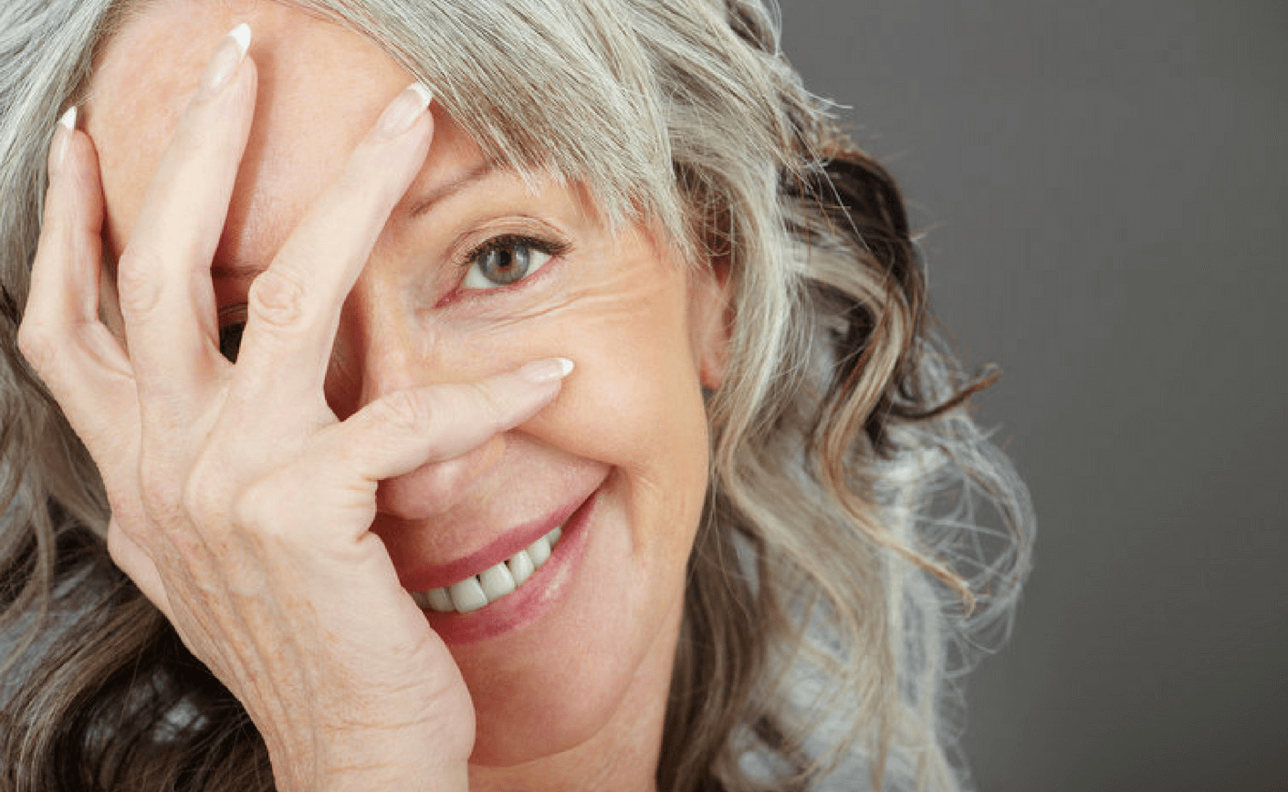 Woman smiling holding face and showing white straight teeth