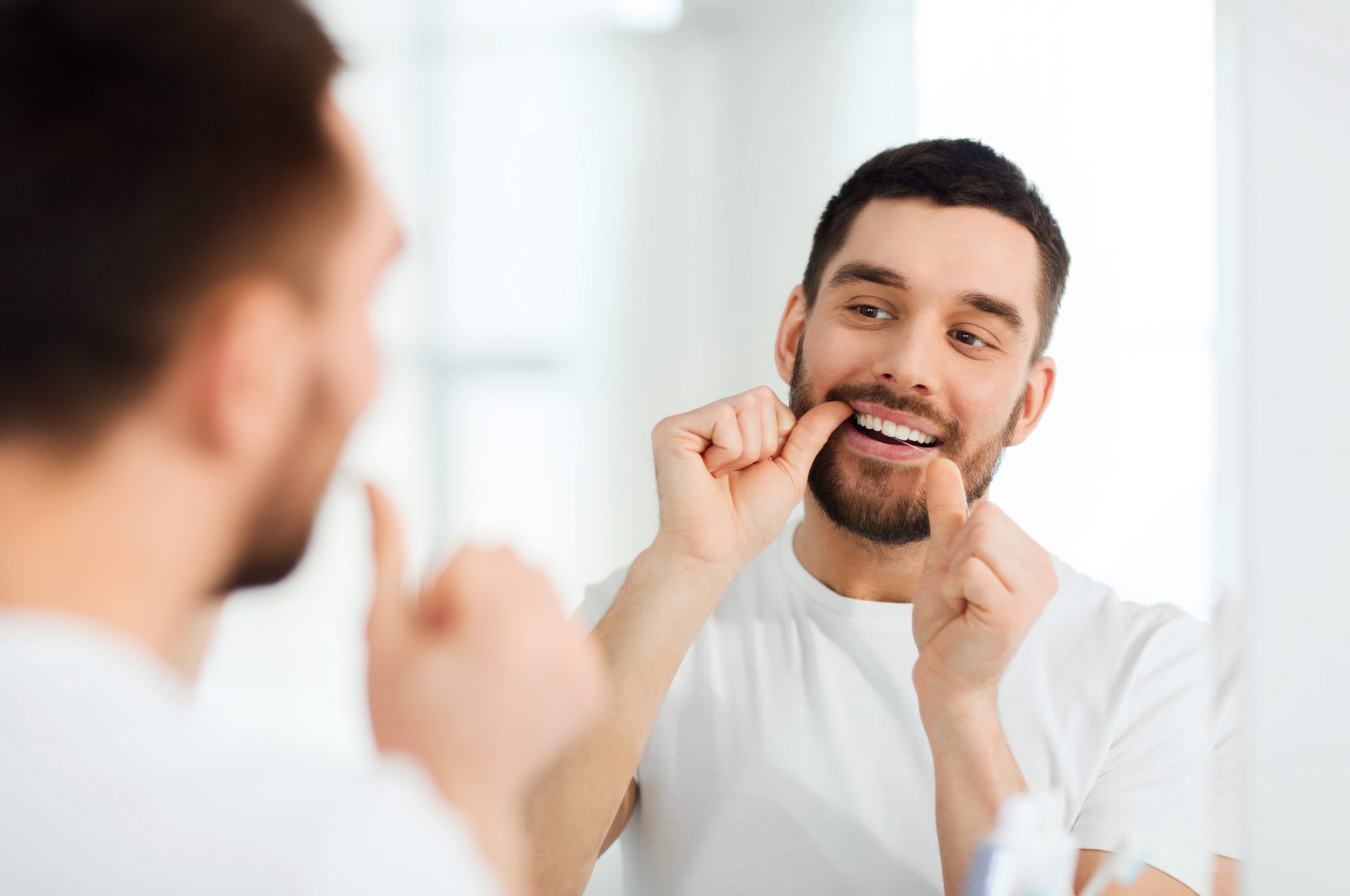 Man flossing his teeth before dental hygienist appointment at Maidstone, Kent