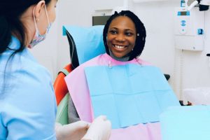 Patient with lost teeth smiling in dental attire in clinic at dental staff member