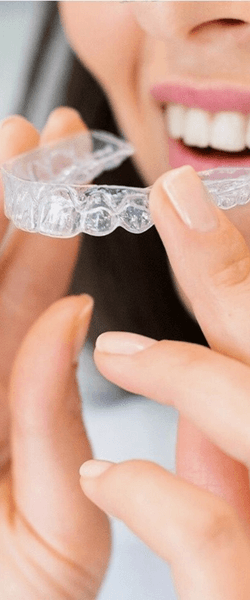 Woman inserting Invisalign braces into mouth 