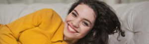 woman with clean teeth smiling on sofa at Maidstone dental practice