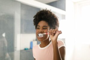 woman brushing her teeth looking in the mirror