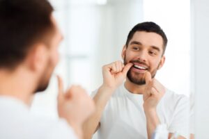 man flossing his teeth after a preventative dental care check up