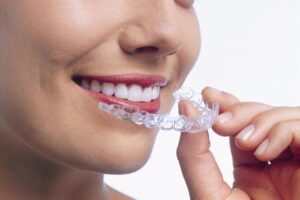 Invisalign - Woman with straight white teeth putting in her Invisalign aligners from Roseacre
