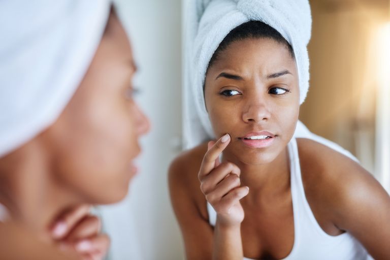 Woman frowning looking in the mirror before her anti-wrinkle fillers appointment